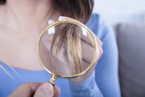 Girl looking at her hair with magnifying glass